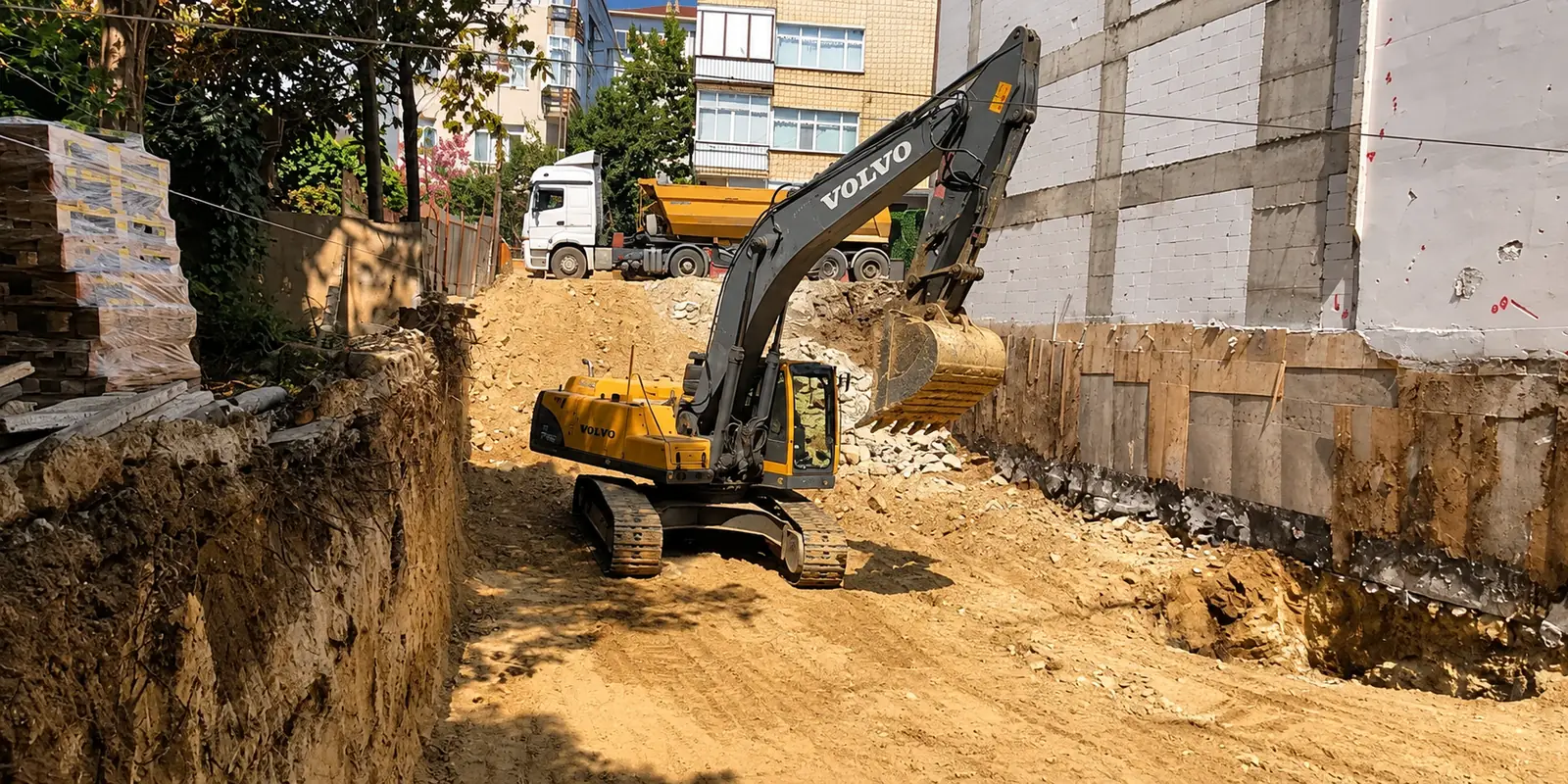 Binaların arasındaki arsada kazı yapan Volvo ekskavatör